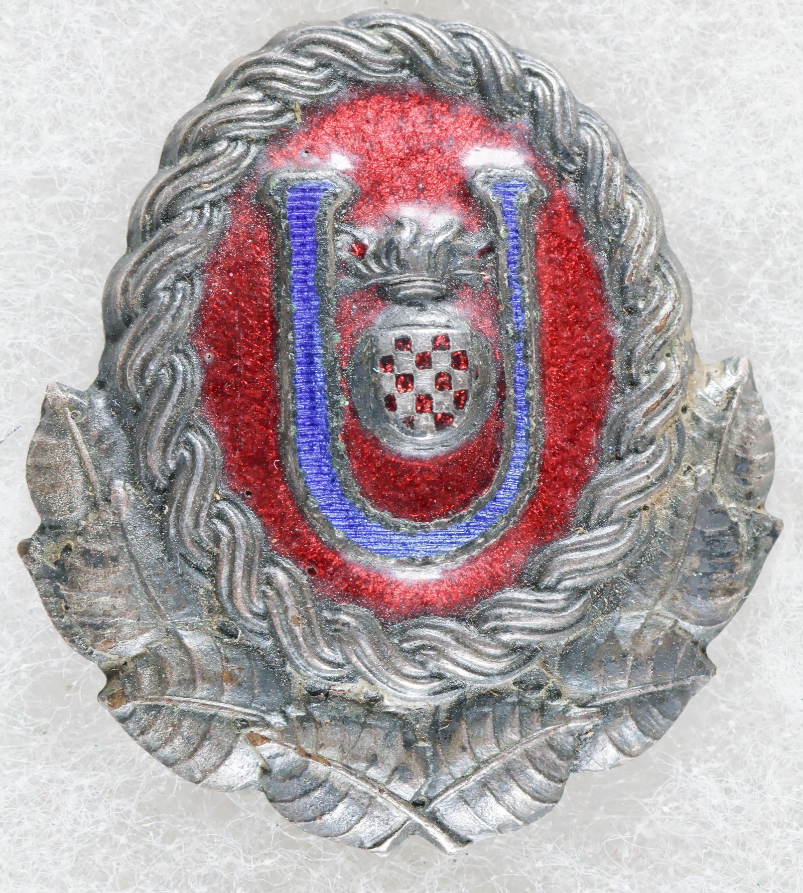 INDEPENDENT STATE OF CROATIA USTASE OFFICER'S CAP BADGE: A rare World War II-era cap badge, 1.25 x 1.5 in., worn by officers of the Ustase, the ruling party of the Independent State of Croatia. The badge is constructed of stamped tombac with a silver-wash f