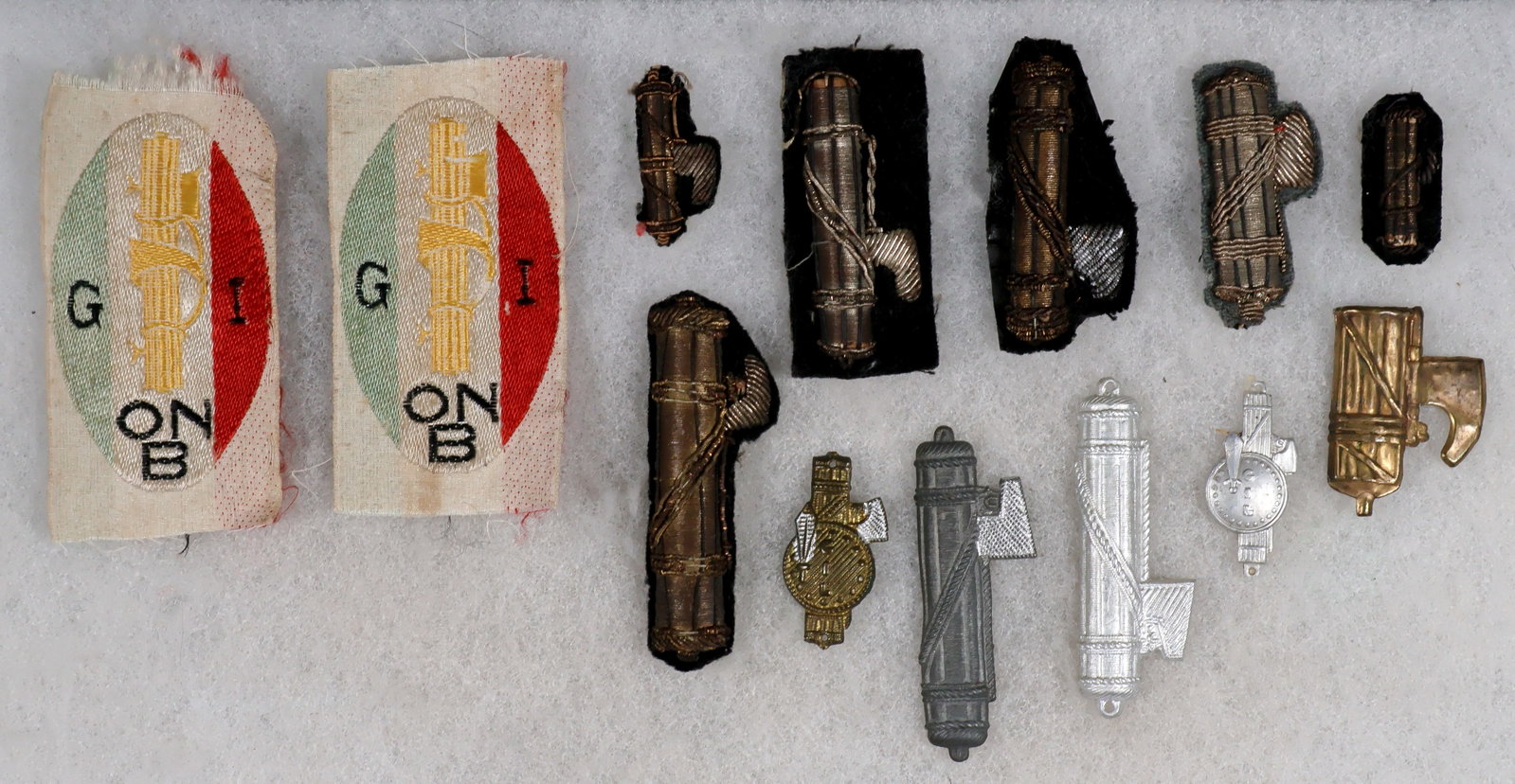 ITALIAN MILITARY UNIFORM INSIGNIA (13): A fine lot of thirteen pieces of Fascist-era Italian uniform insignia, including six of varying sizes featuring embroidered bullion fasces on wool, a further five shell metal fasces, and two