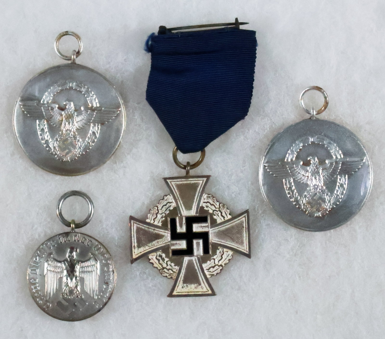 NAZI LONG SERVICE MEDALS (4): Collection of four Nazi Long service medals, Including: one NSDAP Civil Service Faithful Service Medal, in silver for 25 years of service, a silvered tombac Iron Cross backed by an oak leaf wreath wit