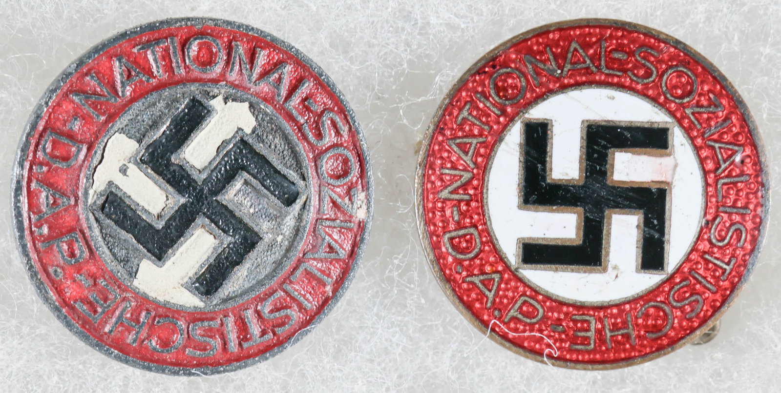 NSDAP PARTY MEMBERSHIP BADGES (2): Good pair of standard NSDAP membership badges awarded to all party members upon acceptance, each approx. 0.75 in. dia., both depicting a red, circular outer border with embossed script ‘National