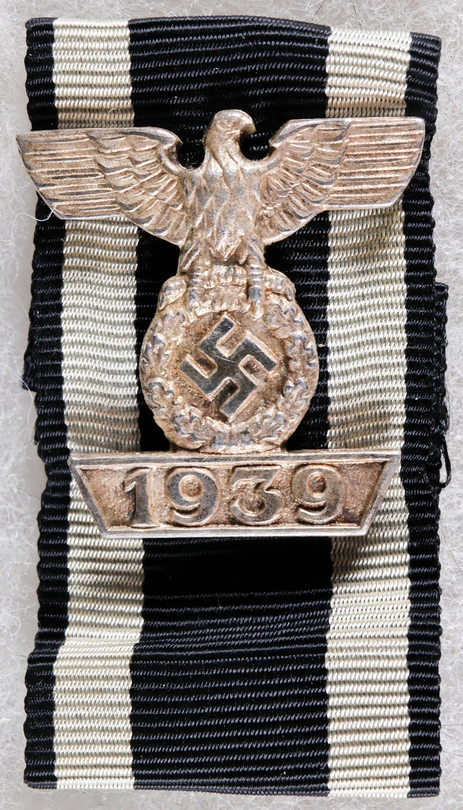 SPANGE TO THE IRON CROSS, SECOND CLASS: A German World War II clasp, 1.25 x 2 in., nickel construction with four horizontal prongs on the reverse, being a ‘spange' to the Iron Cross, Second Class featuring an eagle with a swastika ato