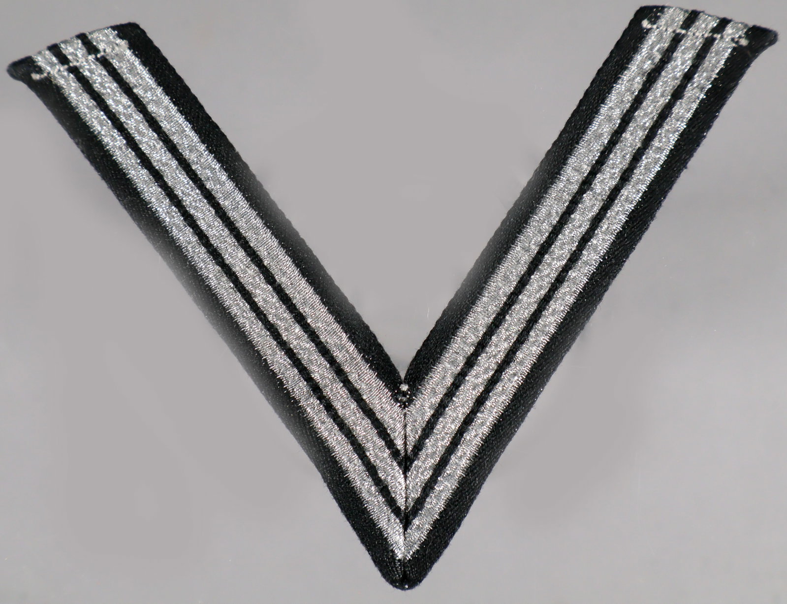 SS HONOR CHEVRON FOR 'OLD CAMPAIGNERS': An SS ‘Ehrenwinkel für Alte Kämpfer’, or Honor Chevron for Old Campaigners, approx. 3.5 x 2.75, for wear on a black uniform tunic, consisting of a single machine woven, metallic