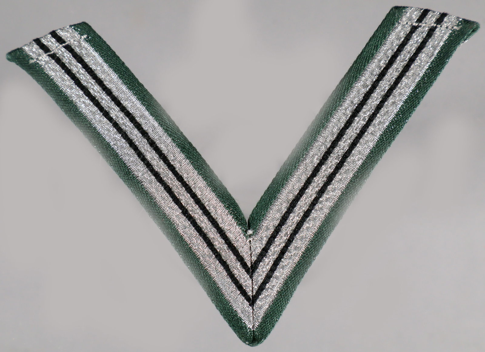 SS HONOR CHEVRON FOR OLD CAMPAIGNERS, FIELD-GRAY: An SS ‘Ehrenwinkel für Alte Kämpfer’, or Honor Chevron for Old Campaigners, approx. 3.5 x 2.75, for wear on a ‘field-gray’ uniform tunic, consisting of a single