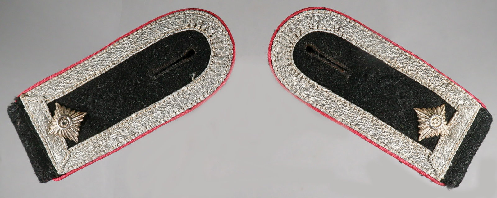 WAFFEN-SS OBERSCHARFUHRER’S SHOULDER BOARDS: A fine pair of Waffen-SS officer’s uniform shoulder boards, each approx. 4.25 x 1.75 in. (folded), constructed of black wool, with a gray wool backing stitched to the underside of the boards