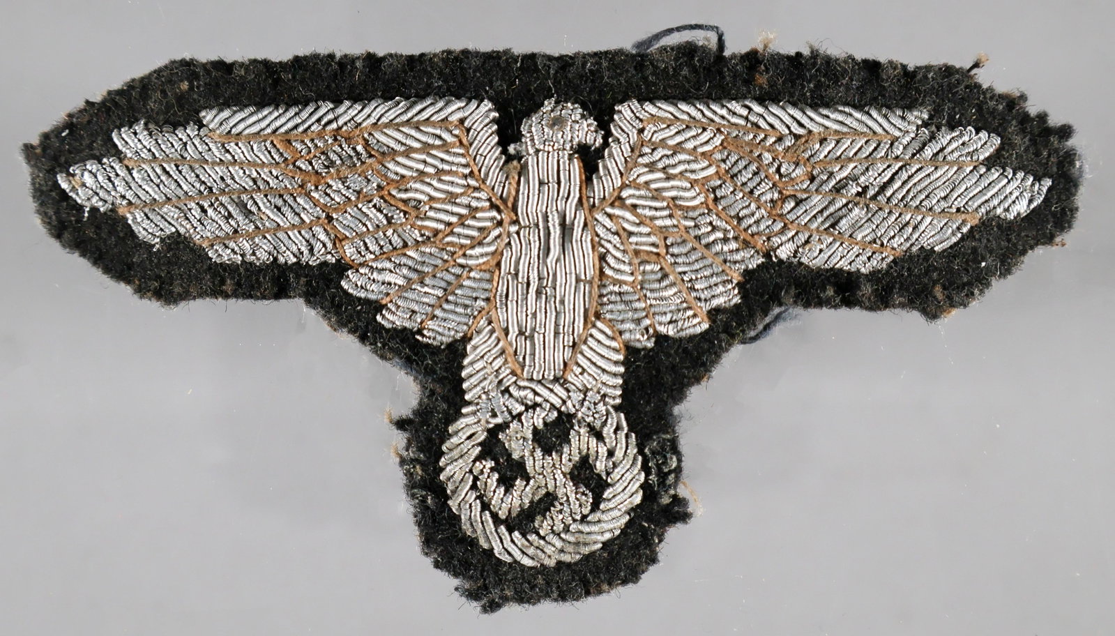 WAFFEN-SS OFFICER'S SLEEVE EAGLE: Waffen-SS officer's sleeve eagle. The eagle is beautifully constructed of silver bullion in two different textures and tones to create contrast, used in conjunction with a lighter stitching meant to