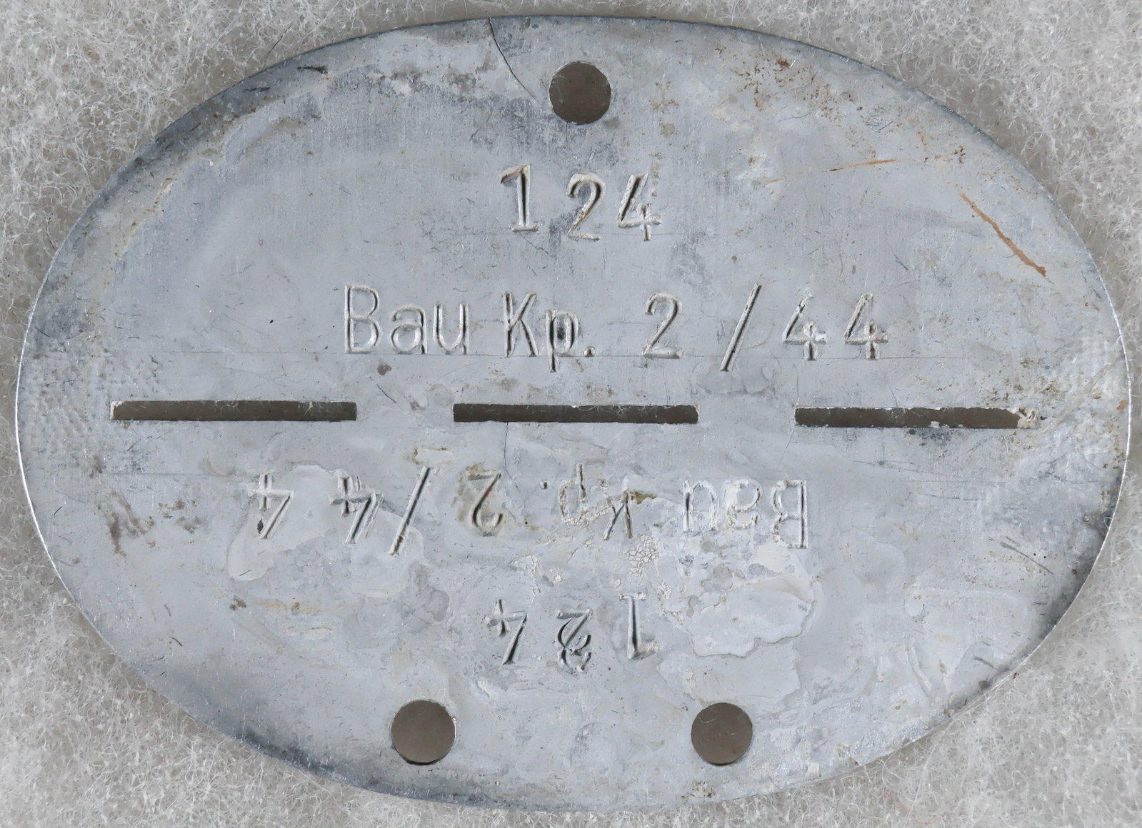 WEHRMACHT CONSTRUCTION UNIT SOLDIER’S IDENTIFICATION DISK: An aluminum Wehrmacht ‘Erkunnungsmark’, or identification disk/dog tag, 2.75 x 2 in., both halves stamped with the owner’s roll number ‘124’ over his unit ‘Bau Kp.