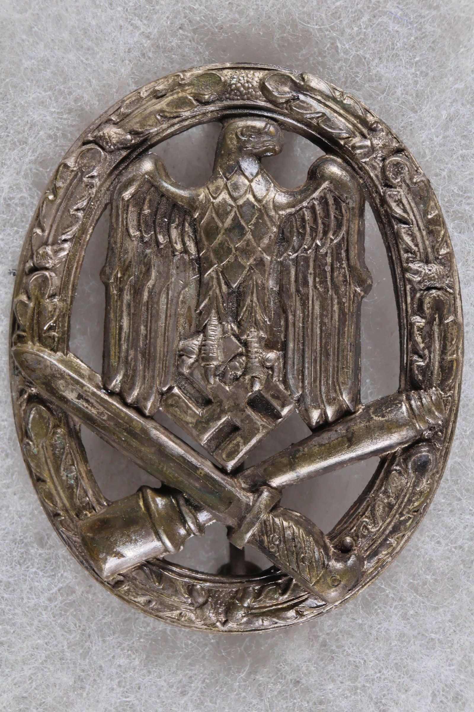 WEHRMACHT GENERAL ASSAULT BADGE: A Wehrmacht ‘Allgemeines Sturmabzeichen’, or General Assault Badge, approx. 1.25 x 2 in., constructed of stamped zinc with a hollow back. Fitted with a vertical pin and catch assembly,