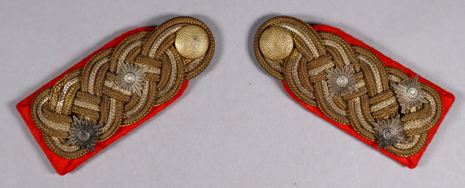 WEHRMACHT GENERALOBERST’S SHOULDER BOARDS: A fine pair of Wehrmacht uniform shoulder boards, each approx. 4 x 1.75 in., constructed of red wool decorated with interwoven metallic brass and silver braided cords. The underside of each is fitted
