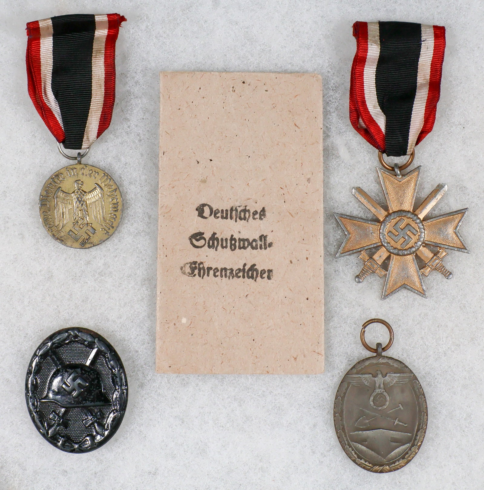 WEHRMACHT MEDALS (4): Good lot of four Wehrmacht medals, includes, the War Merit Cross, Second Class with Swords, West Wall Medal with envelope, Wound Badge in Black and Wehrmacht Long Service Award, Third Class. The War M