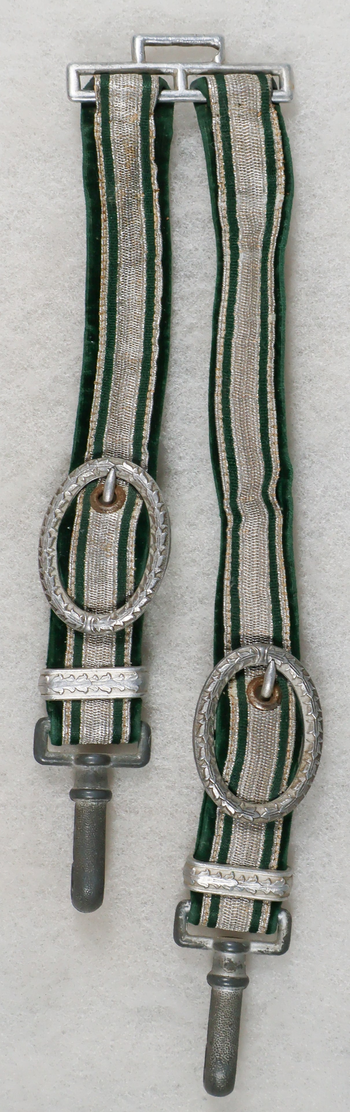 GERMAN CUSTOMS OFFICER'S DAGGER HANGER: Green velvet construction with silver thread and tresse, aluminum belt loop hanger, and aluminum oval buckles and keepers, both showing oak-leaf motif and clips. Solid and secure with no damages,