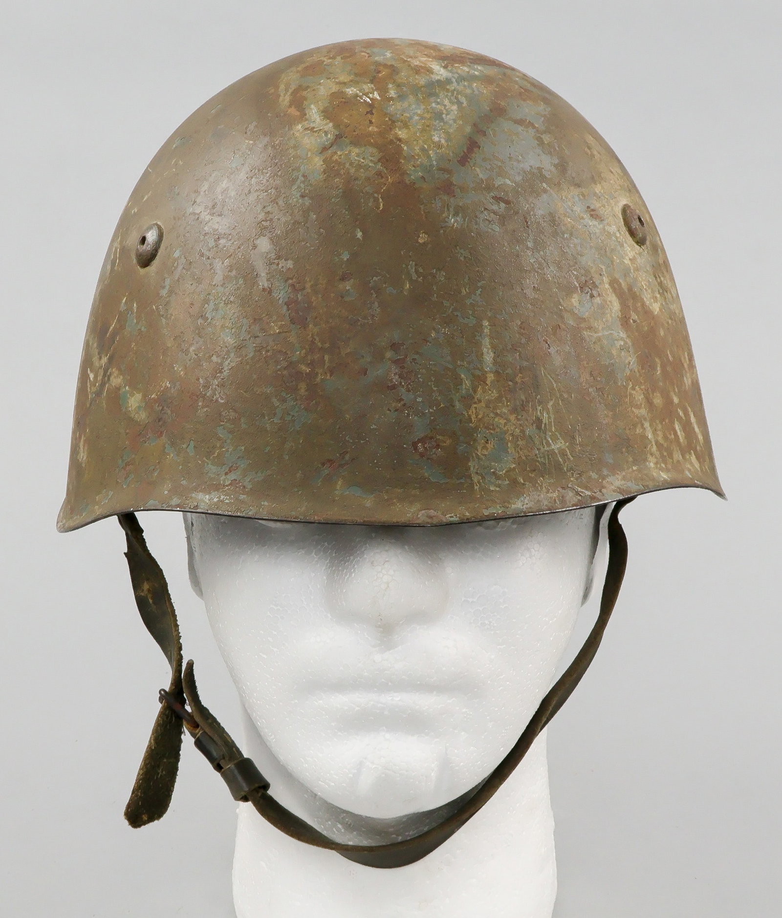 ITALIAN M33 HELMET: Steel M33 combat helmet, standard issue to the armed forces of Italy during World War II. The helmet is refinished postwar green-brown overall, and bears a riveted vent hole at each side, with a third