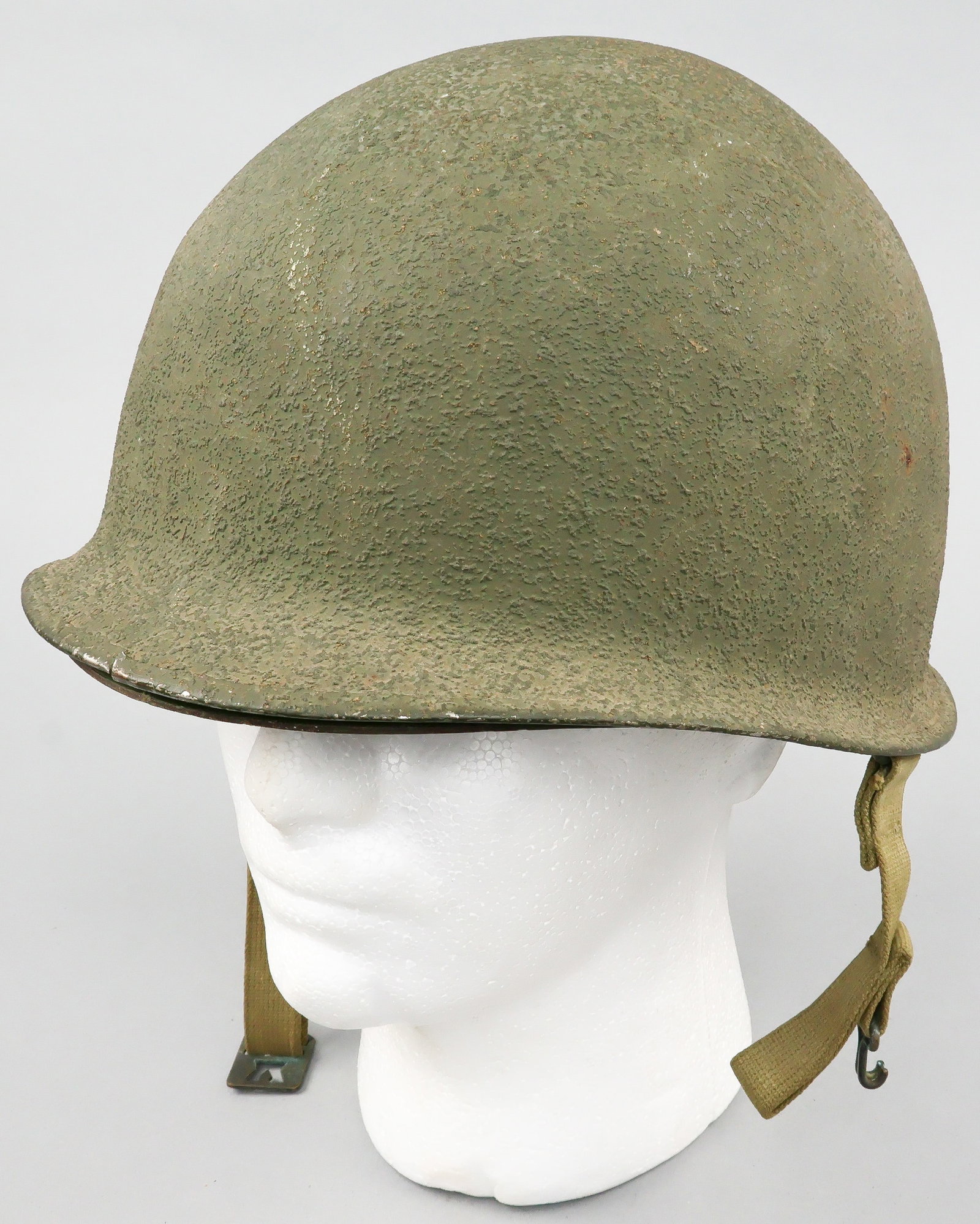 U.S. M1 FIXED BALE HELMET: Early World War II U.S. M1 front seam, fixed bale helmet, with stainless steel rim and original sewn-in chin straps with flat brass first type buckle. The exterior features its original cork-textured 