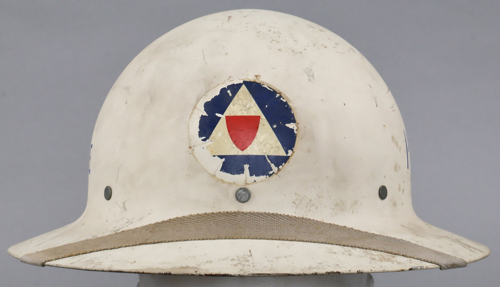 U.S. CIVIL DEFENSE AUXILIARY POLICE HELMET: A U.S. World War II-era civil defense helmet, manufactured by McCord, with Office of Civil Defense auxiliary police decal at front and the stenciled designation ‘Police’ on both sides. The