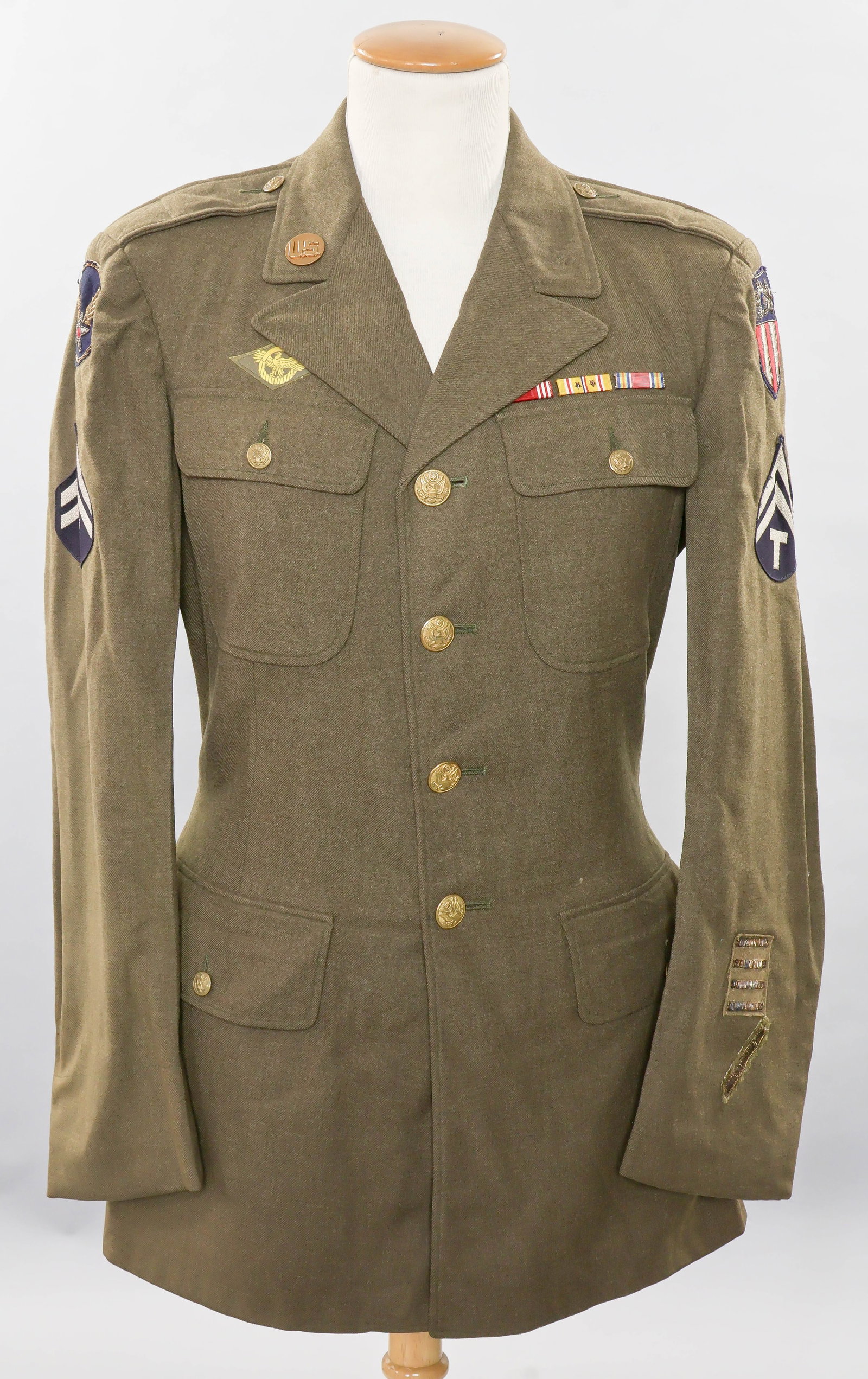 CHINA-BURMA-INDIA USAAF JACKET WITH THEATER-MADE PATCHES: Excellent World War II-period M1939 Class A uniform jacket worn by a member of the USAAF’s China-Burma-India command. Constructed of green wool, the tunic is closed at front by four gilt