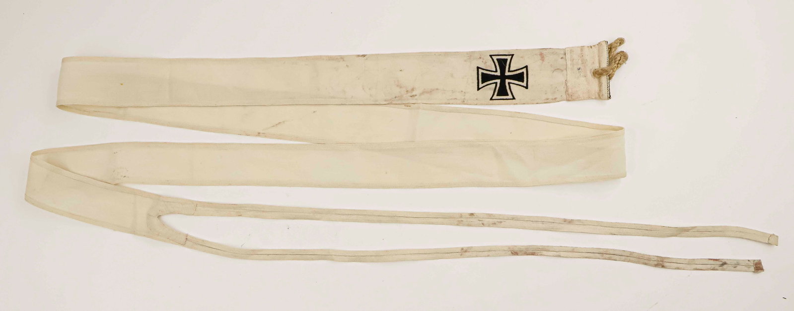 KRIEGSMARINE COMMODORE PENNANT: World War II pennant, 50 x 2 in., bearing the image of an Iron Cross at the top. On the reinforced section bearing two rope handles is a faded Kriegsmarine ‘Eagle M' acceptance stamp. At the