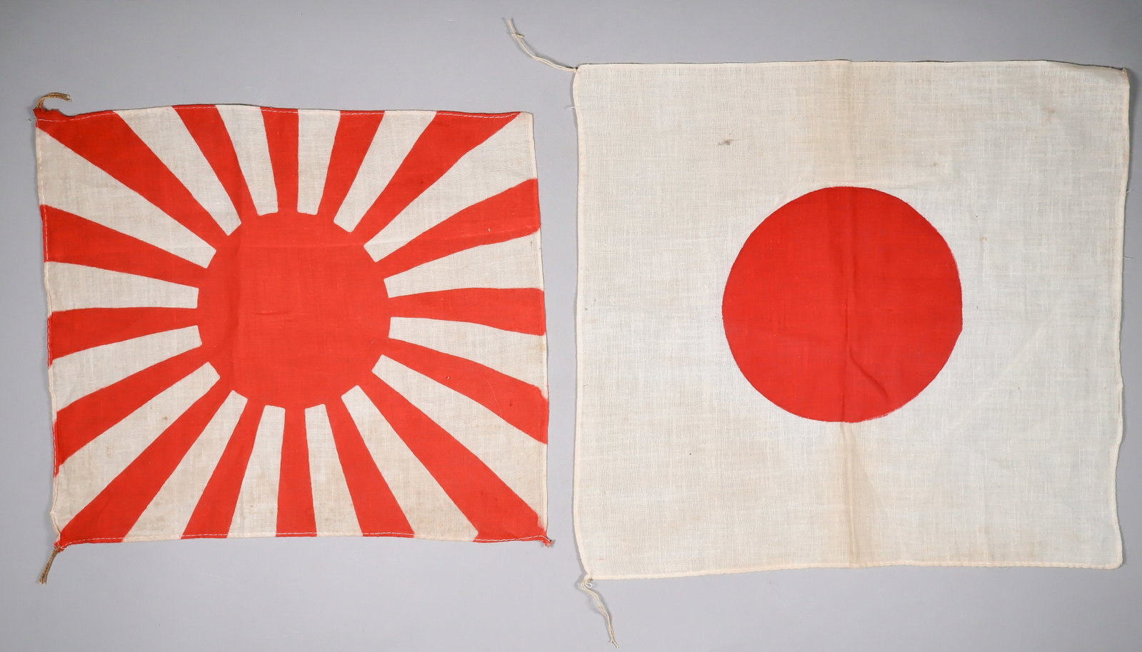 JAPANESE ARMY AND NATIONAL FLAGS (2): Pair of World War II-era cotton two-sided Japanese flags, each approx. 12.5 x 10.75 in., one a Japanese Army flag, the other a Japanese national flag. Both bear ties at either end of the hoist. Near