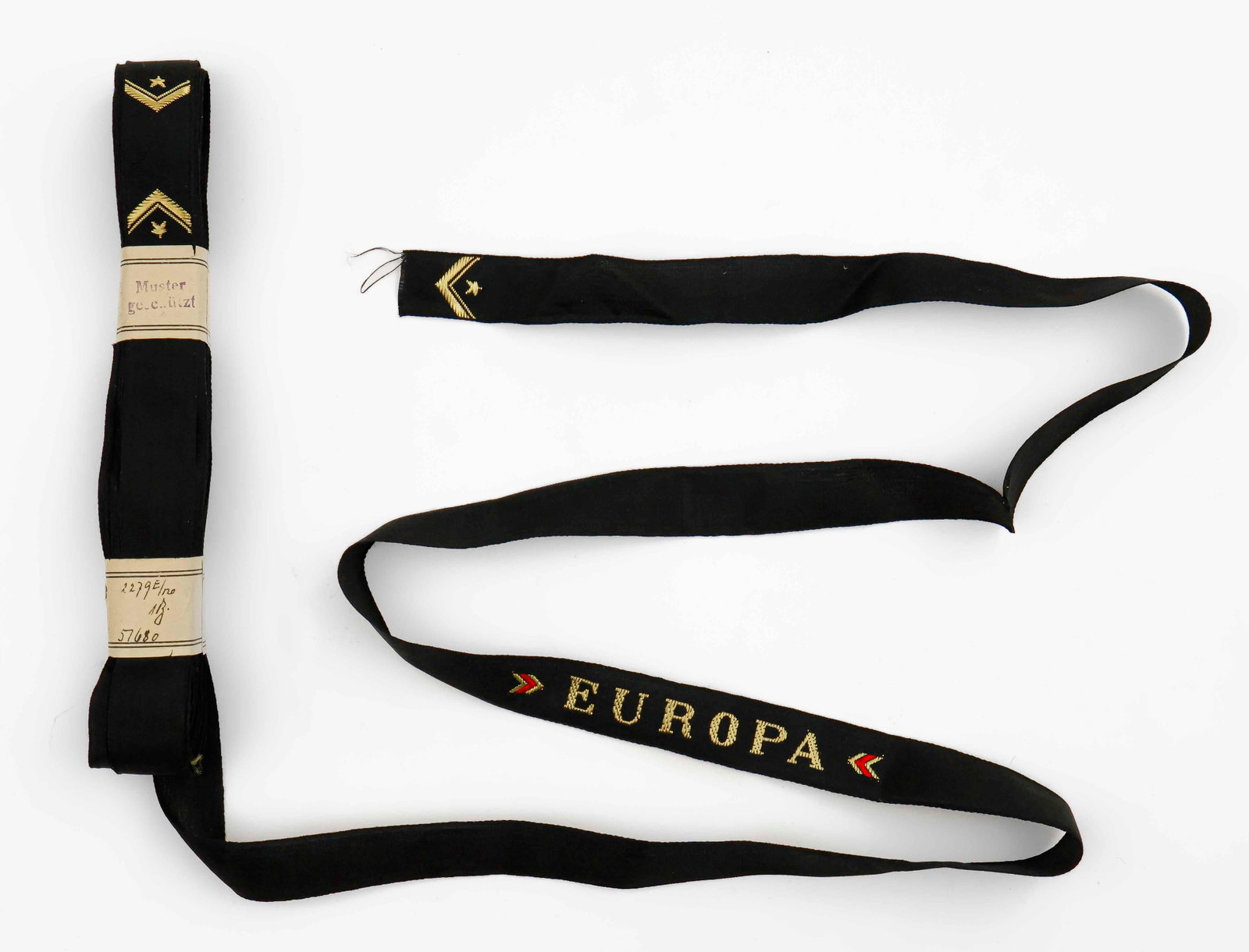 ‘EUROPA’ CAP TALLIES FOR CHILDREN (10): Lot of ten uncut BeVo sewn cap tallies for a child’s Kriegsmarine cap. The name ‘Europa’ is finely woven in gilt thread on a black field. SS Europa, later the SS Liberte, was a