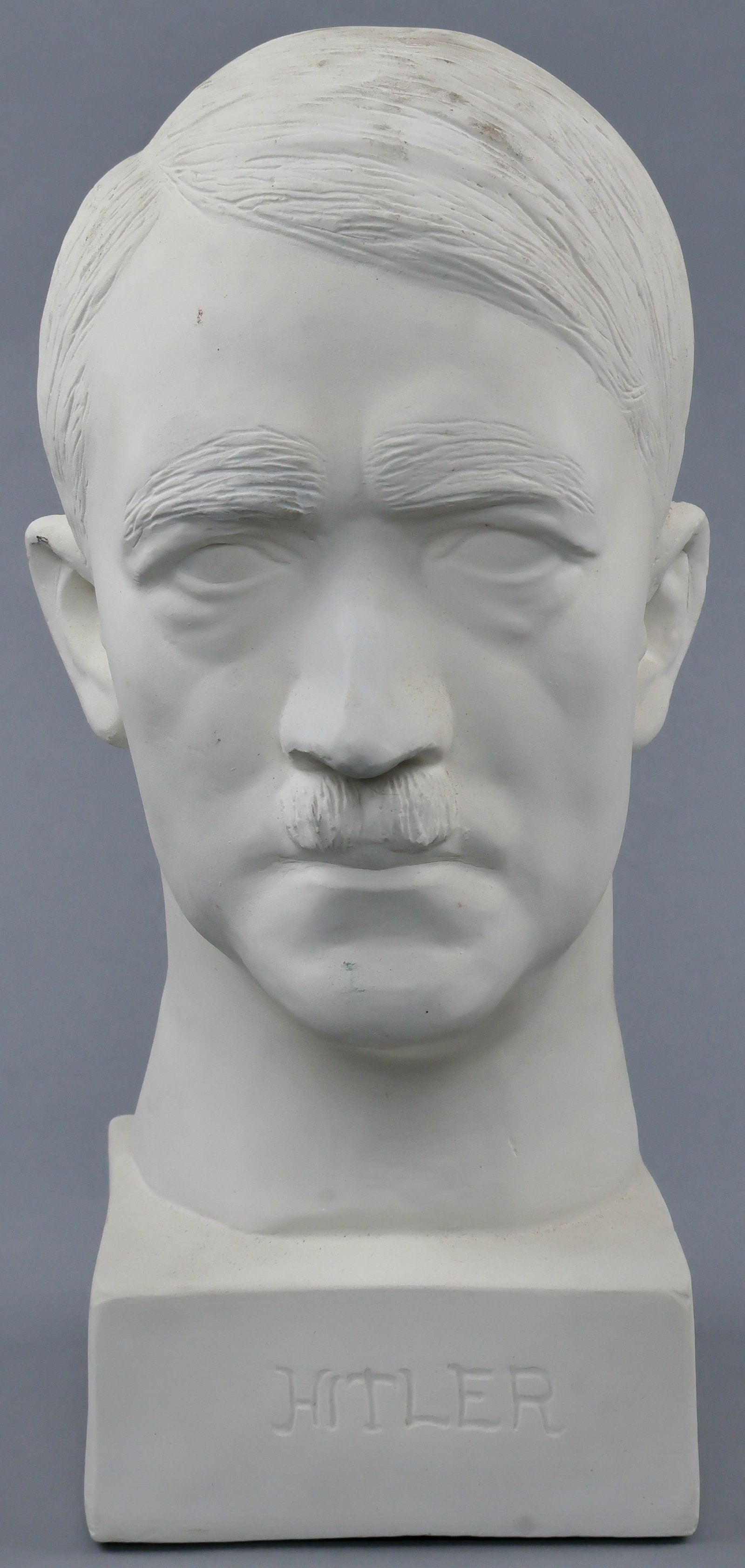 BUST OF ADOLF HITLER: A handsome ceramic bust of Hitler, 14 in. tall on a 5 in. square, unglazed and possibly a period piece, shows the Fuhrer in fine detail, signed on the back of the initials ‘LB’. Very good