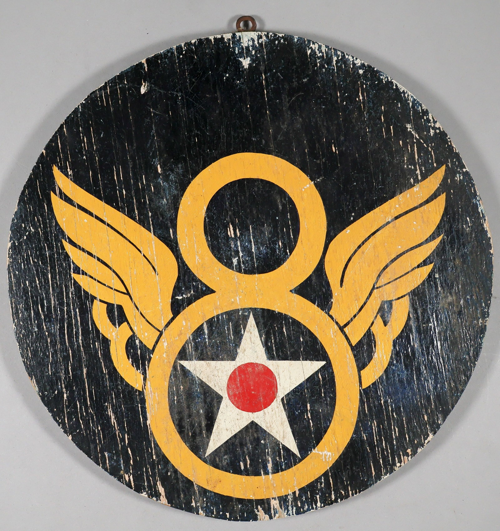 8TH AIR FORCE WOOD AIR BASE PLAQUE: Hand-painted wooden plaque, 11.75 in. dia. plywood painted with the emblem of the American 8th Air Force on one side, white on the reverse, with an old screw-in ring fitted at top. Typical wear and
