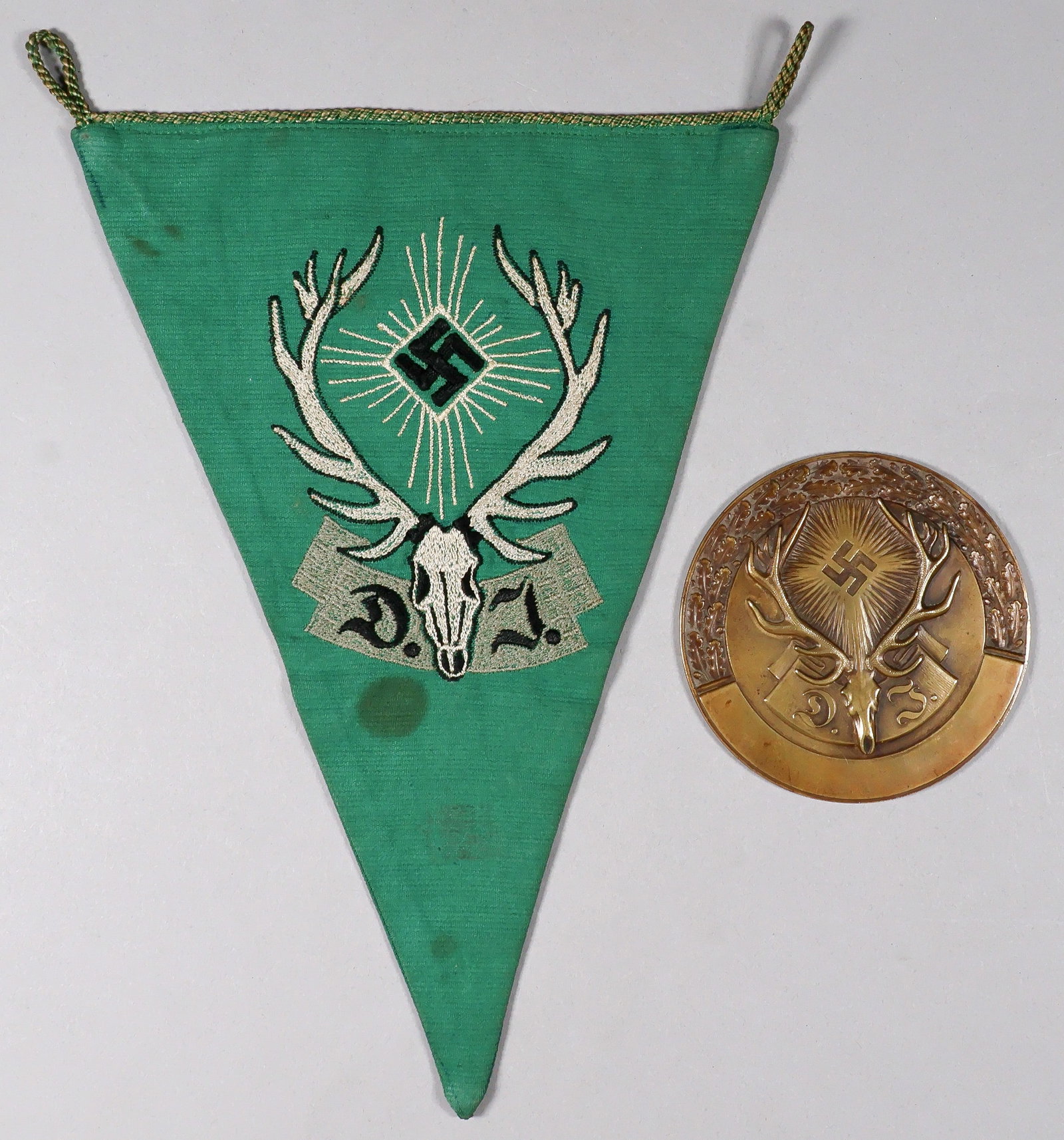 GERMAN HUNTING ASSOCIATION PLAQUE AND PENNANT: Brass plaque, 3.125 in. diameter, associated with the German Hunter’s Association (Deutsche Jagerschaft), the official hunting society of Nazi Germany, led by Hermann Goring. Membership was