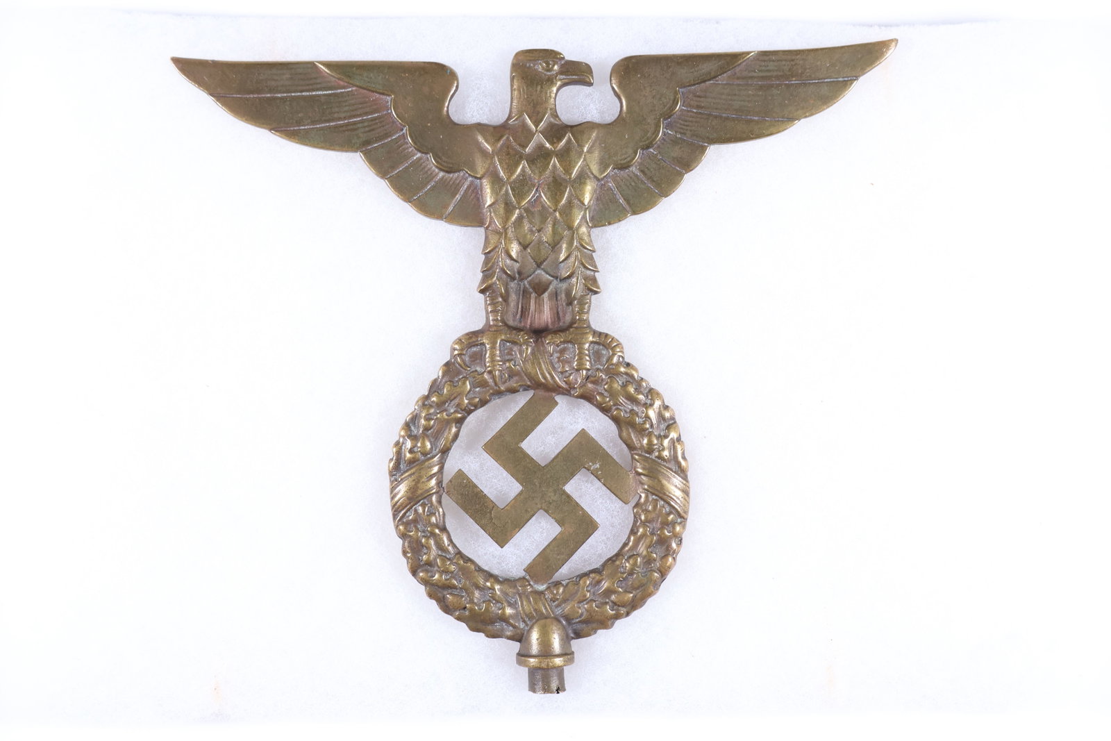 NSDAP FLAG POLE TOPPER: Brass NSDAP flag pole topper, approx. 8 x 7 in., in the form of a national eagle clutching a wreath, with a mobile swastika in the center. A bit oxidized, unmarked. Very good.