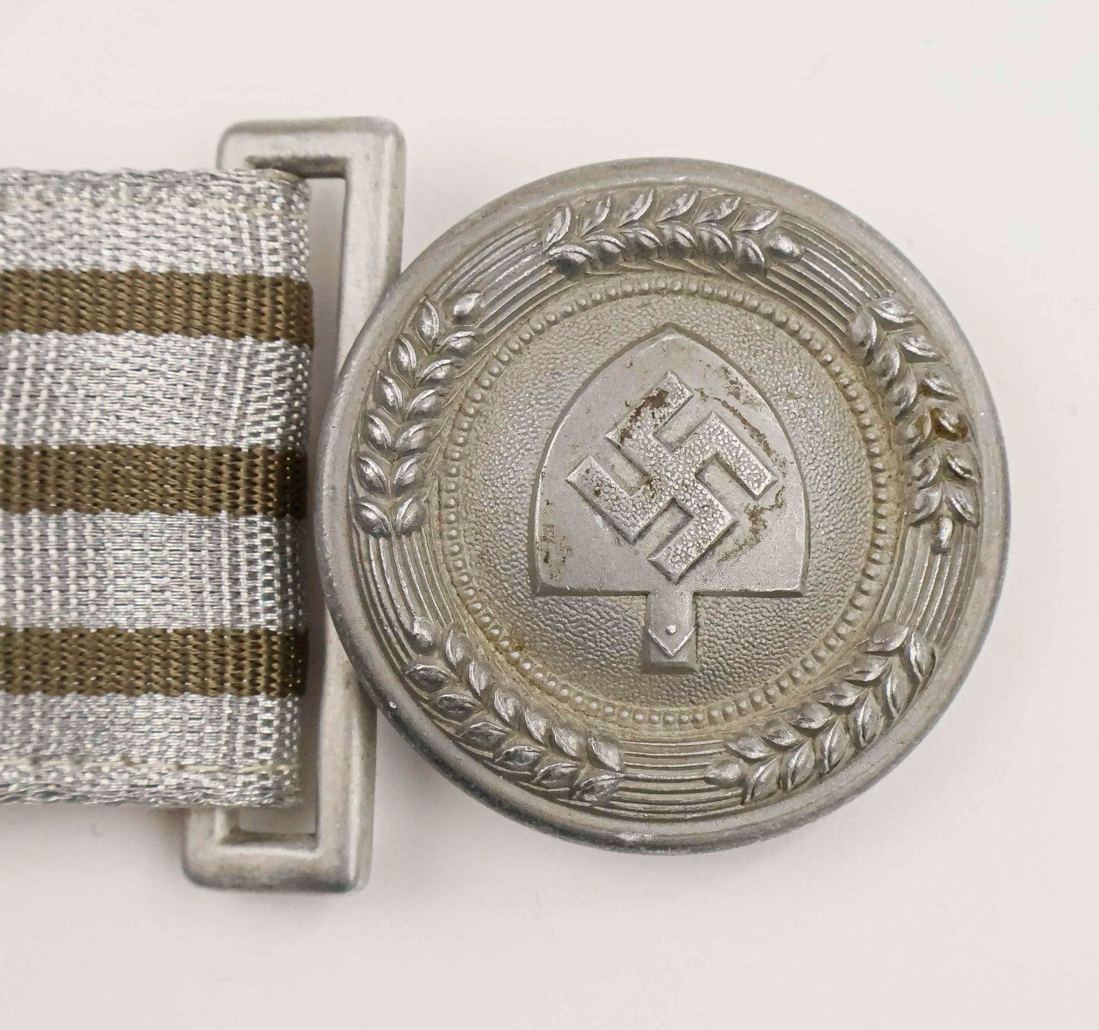 RAD OFFICER’S BROCADE BELT AND BUCKLE: Rare RAD brocade officer’s dress belt, 51 in. long, with beige cloth backing. The unmarked circular aluminum buckle, approx. 2 in. diameter, bears the insignia of the Reichsarbeitsdienst
