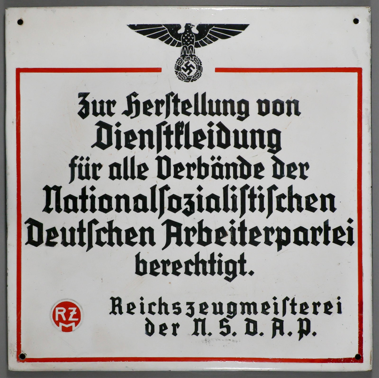 REICHSZEUGMEISTEREI ENAMEL RZM SIGN: Rare enamel RZM advertising sign, 15 in. sq., depicting the 1934 version of the German national eagle at the top. The text within the red border reads: ‘Zur herstellung von Dienstkleidung fur