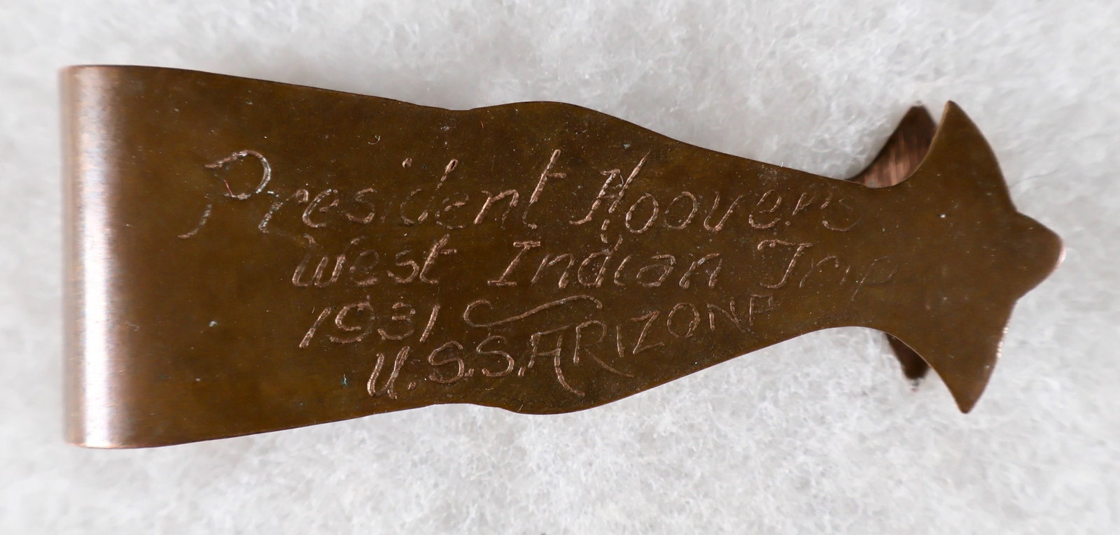 USS ARIZONA-HERBERT HOOVER SHIP RELIC NAPKIN HOLDER: An authentic artifact from the second maiden voyage of the ill-fated USS ARIZONA, a stylized copper place setting which served as a nameplate and napkin holder, 1 x 4 in., commemorating a private brea