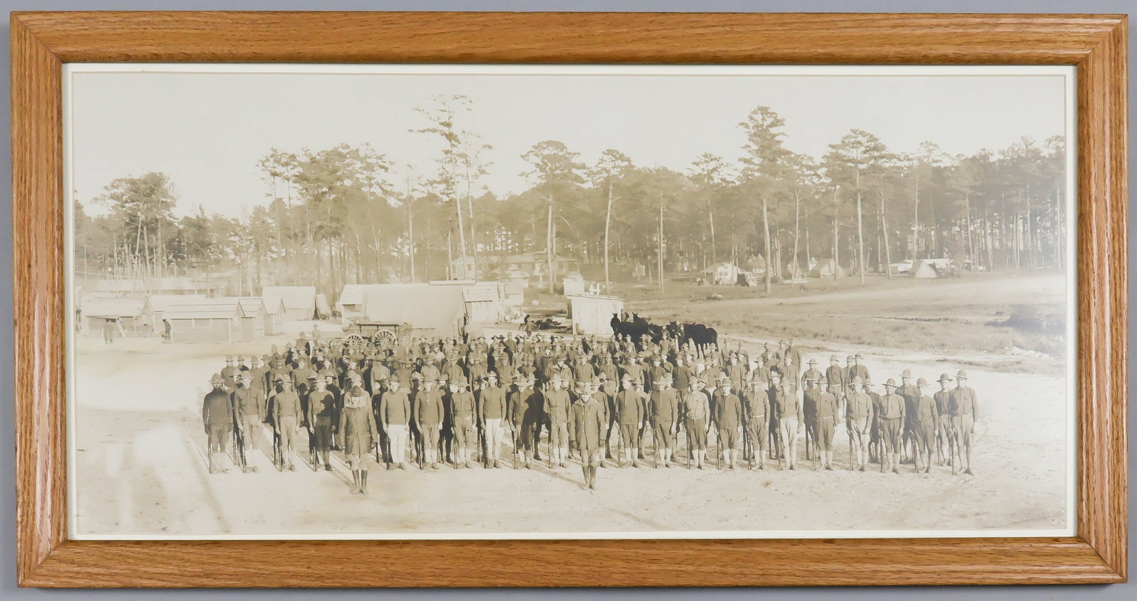 WORLD WAR I SOLDIERS IN TRAINING: Fine large photograph of an unidentified company of American infantrymen ca. 1916, 31.25 x 14.5 in. (sight), the men shown in line with some horse and wagons in the background, with temporary