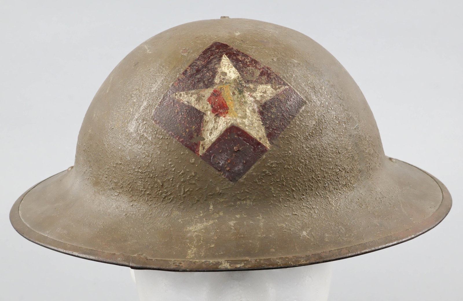 2ND INFANTRY DIVISION PAINTED M1917 HELMET: A fine example of a World War I U.S. soldier’s M1917 steel combat helmet, retaining its original green-brown sawdust-textured finish. Most notably, the front of the helmet displays the hand-pain