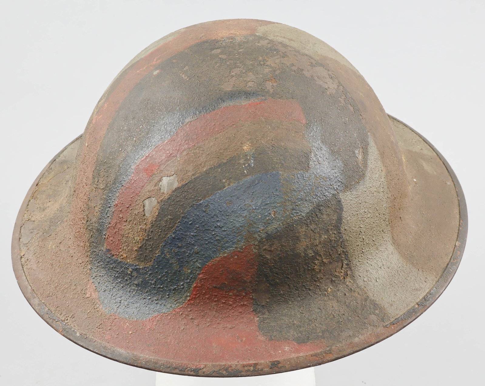 42ND INFANTRY DIVISION CAMOUFLAGE-PAINTED M1917 HELMET SHELL: A fine example of a World War I U.S. soldier’s M1917 steel combat helmet, hand-painted overall with a camouflage pattern of brown, gray, dark green and red, and displaying at the front the hand-