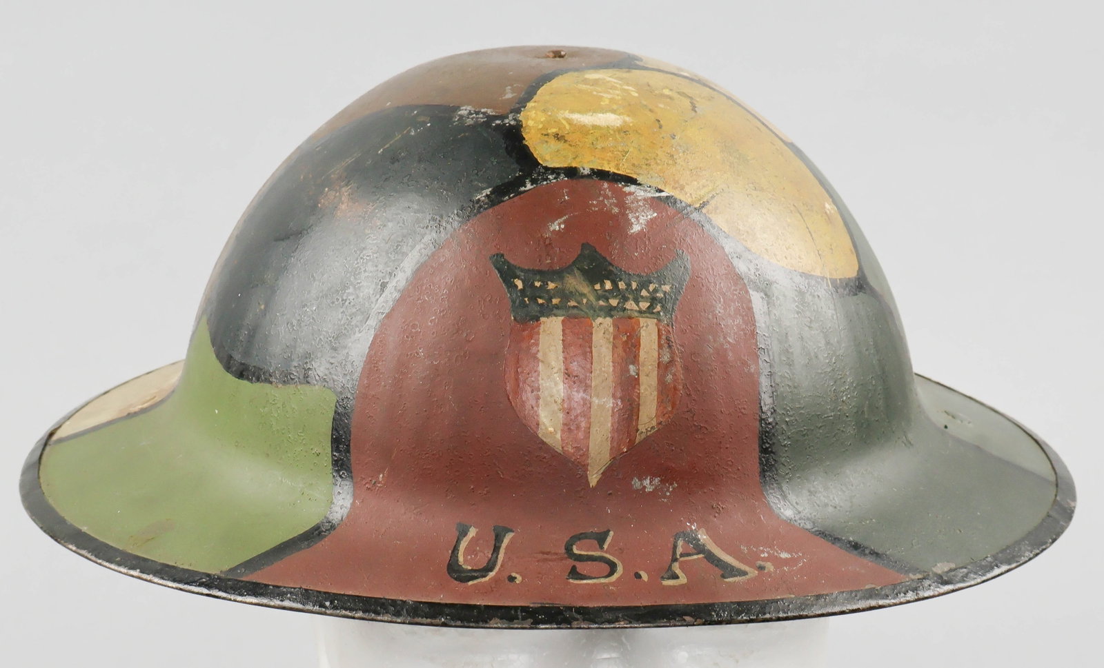 U.S. SOLDIER’S NAMED AND PAINTED MARK I BRODIE HELMET: A fine example of a World War I British Helmet, Steel, Mark I, commonly known as the ‘Brodie helmet’. This example, clearly issued to an American soldier, has been vividly hand-painted ove