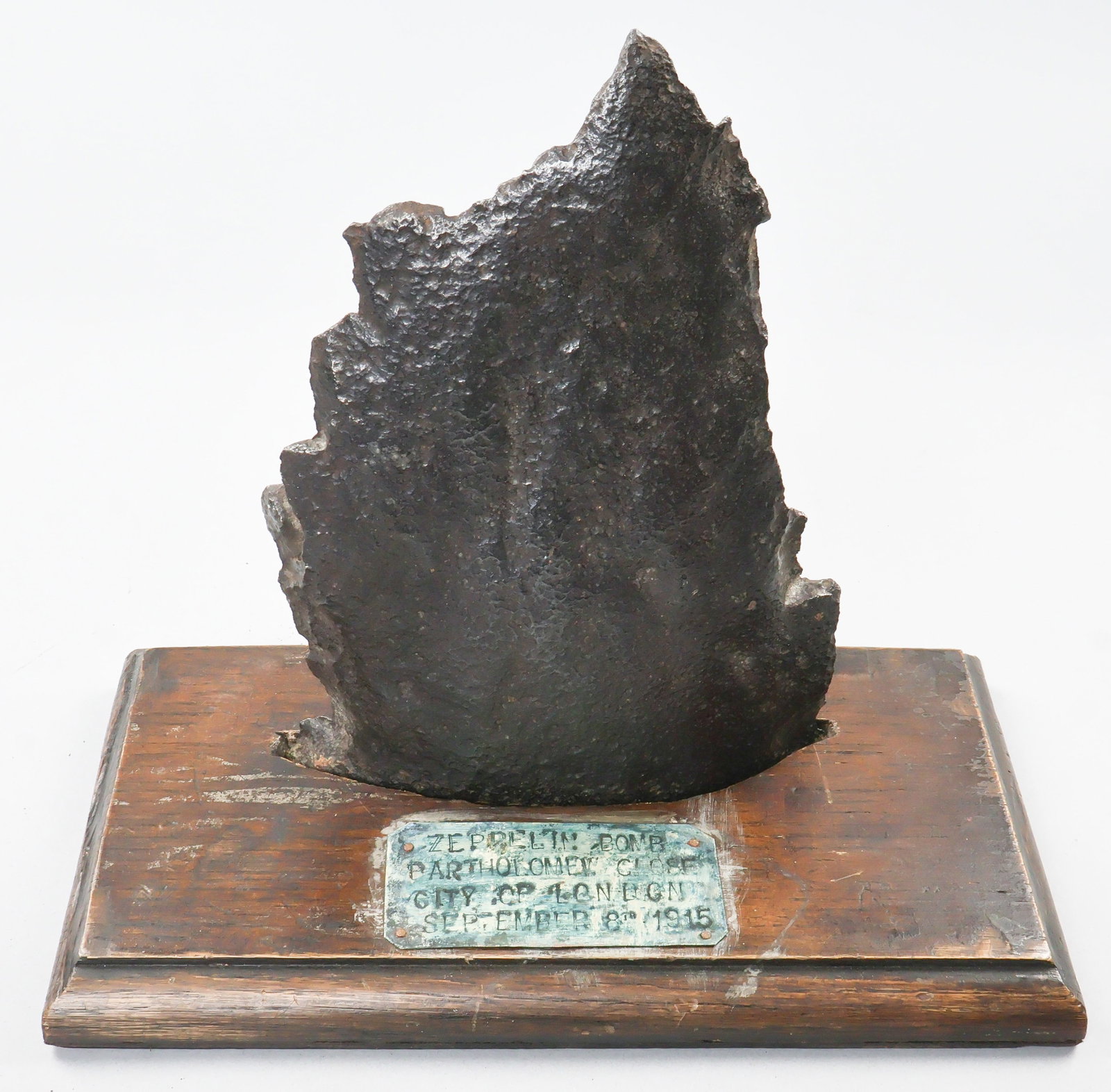 WORLD WAR I ZEPPELIN BOMB RELIC: A 7 in. x 10 in. fragment of steel from a Zeppelin-dropped bomb that detonated in London, September 1915. The relic bears an attractive patina and is set in a custom-designed wood display with plaque