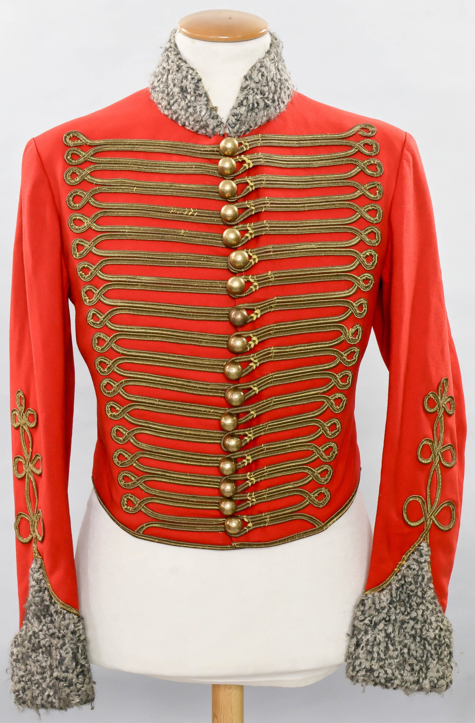 BRITISH ARMY HUSSAR’S PELISSE JACKET COSTUME: A vintage film costume reproduction of a Napoleonic-era British Army hussar’s ‘pelisse’, or jacket, constructed of red wool with white and gray fur at the collar and cuffs. The jacke