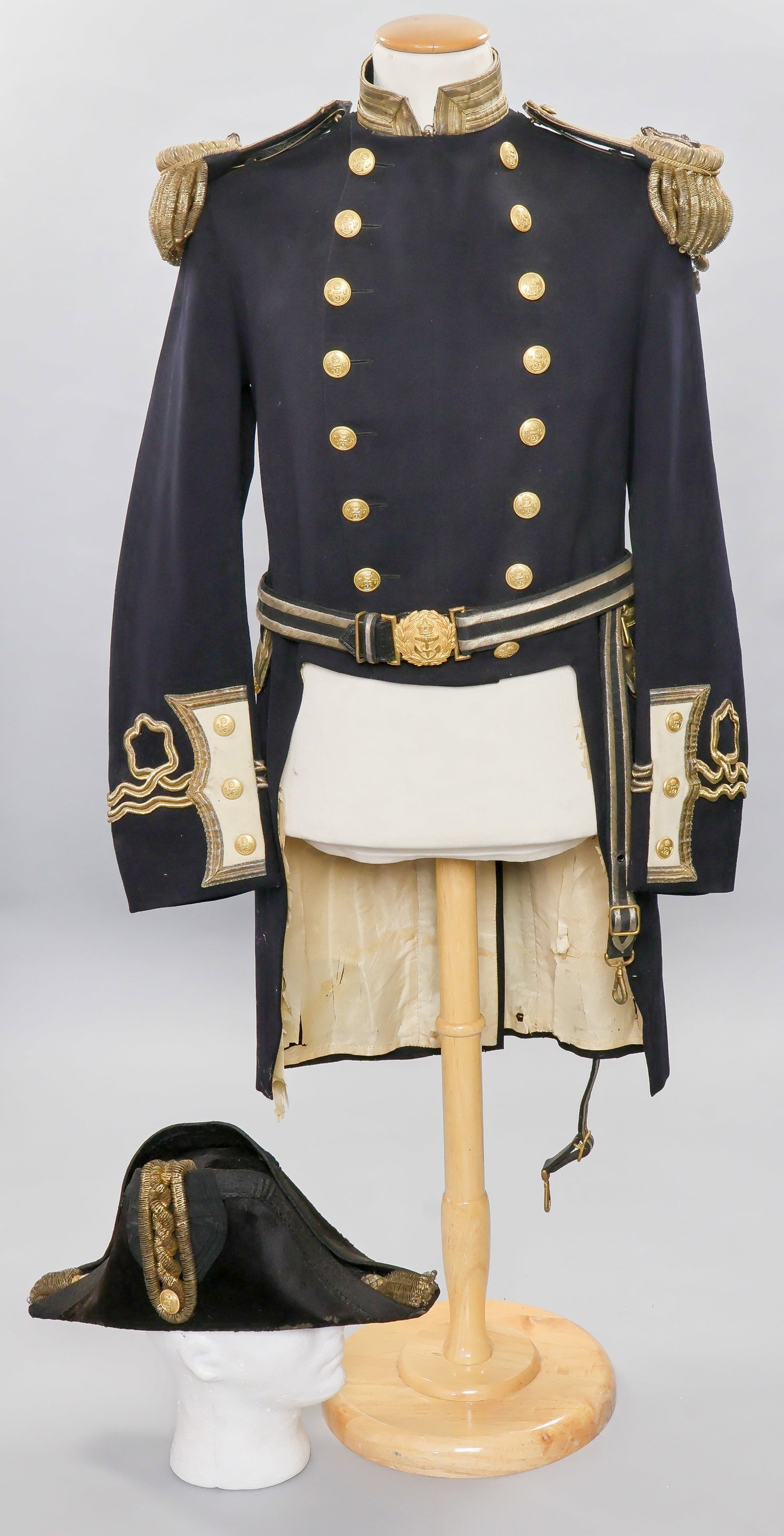CA. 1870'S BRITISH ADMIRAL'S BICORNE HAT, FROCK COAT, AND BELT: 19th Century Royal Navy Admiral's Full Dress Uniform Ensemble. A magnificent and near-complete Royal Navy flag officer’s full dress uniform, circa 1870–1900 pattern. This impressive