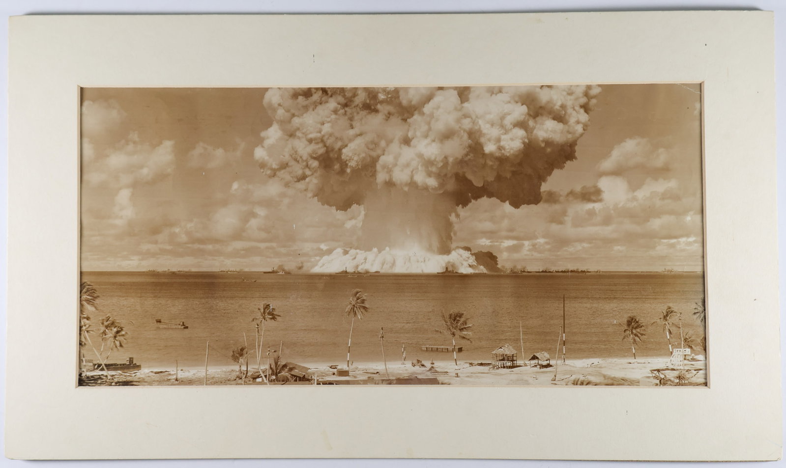 BIKINI ATOLL NUCLEAR PHOTO: An amazing original photograph, 17.5 x 8.5 in. mounted to a 21.5 x 12.5 board, depicts a test off Bikini Atoll from ‘Operation Crossroads’, specifically Test Baker, which involved many