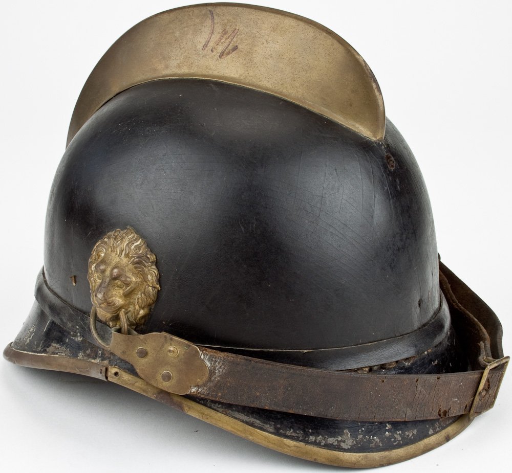 GERMAN FIREMAN'S HELMET: GERMAN FIREMAN'S HELMET Ca. 1915 German fireman's helmet, hard leather body with brass rib at top, lion head ornaments at sides retain chin strap which remains intact. Liner worn but largely intact. A