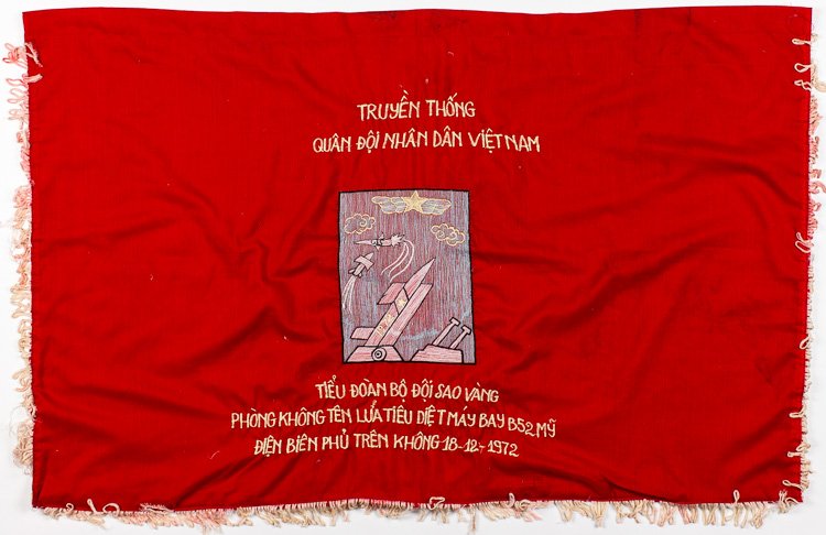 NORTH VIETNAMESE BANNER CELEBRATES B-52 DESTRUCTION: NORTH VIETNAMESE BANNER CELEBRATES B-52 DESTRUCTION Simply-constructed North Vietnamese celebratory hanging banner 39"" x 25"" rayon embroidered with an image of a SAM missile on a launcher with a sec