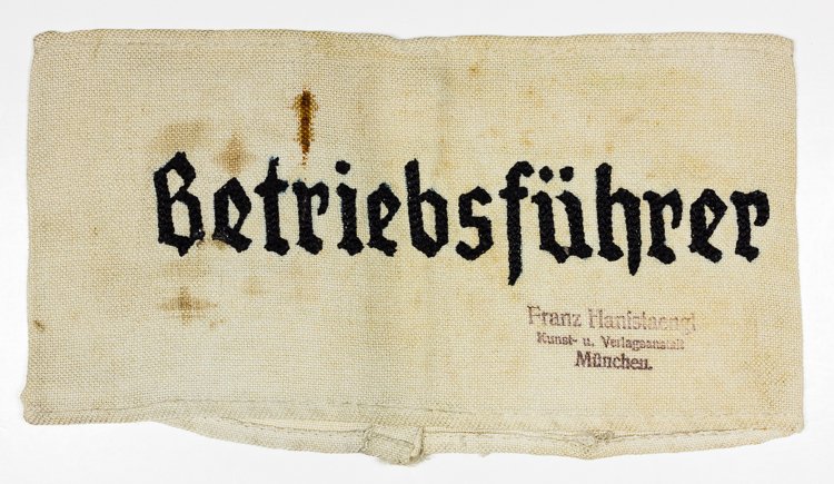 "BETRIEBSFUHRER" ARMBAND: "BETRIEBSFUHRER" ARMBAND Armband issued to an operations manager, white cotton, 15" x 4", with black embroidered lettering. Stamped with the name of the highly-respected art publishing house "Franz Ha