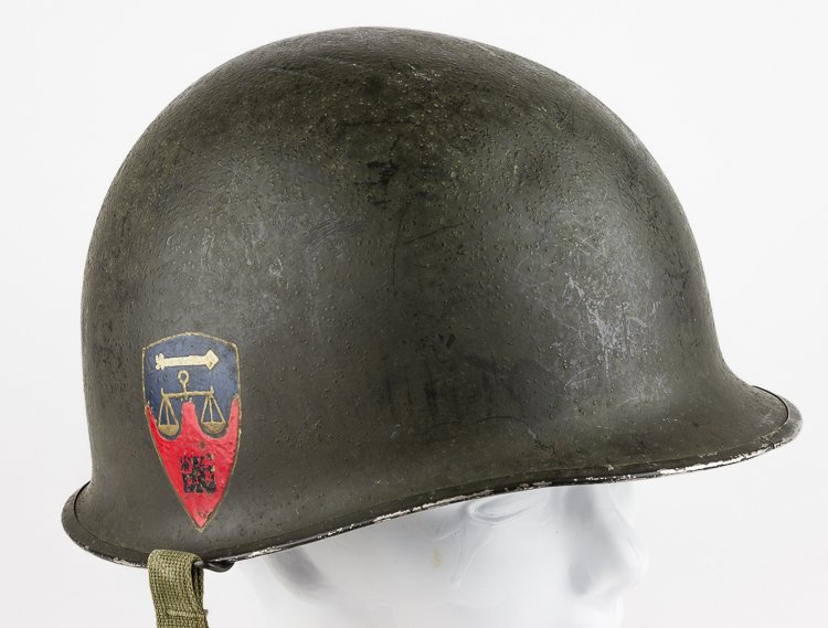 NUREMBERG WAR CRIMES TRIALS AMERICAN GUARD'S HELMET: NUREMBERG WAR CRIMES TRIALS AMERICAN GUARD'S HELMET Green "sand finish" M1 combat helmet issued to a guard at the post-war Nuremberg War Crimes Trials. The shield insignia of the trials has been hand-
