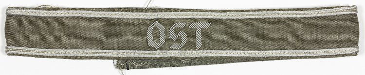 OCCUPIED POLAND "OST" SLEEVE TITLE: OCCUPIED POLAND "OST" SLEEVE TITLE Very rare grey cloth sleeve title, 19" x 1", with the legend "OST" hand-embroidered in silver bullion thread, and the edges outlined with silver piping. This cufftit