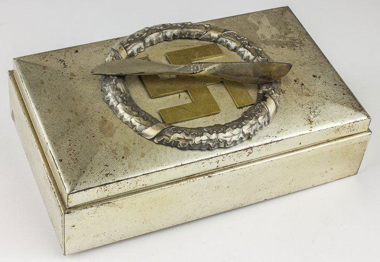 GERMAN FLIEGERKORPS CIGAR BOX: GERMAN FLIEGERKORPS CIGAR BOX Cigar box believed to have been gifted to a Fliegerkorps member, 9" x 5 «" x 2 «" all metal with silver finish, the top hinged lid decorated with a gold static swastika