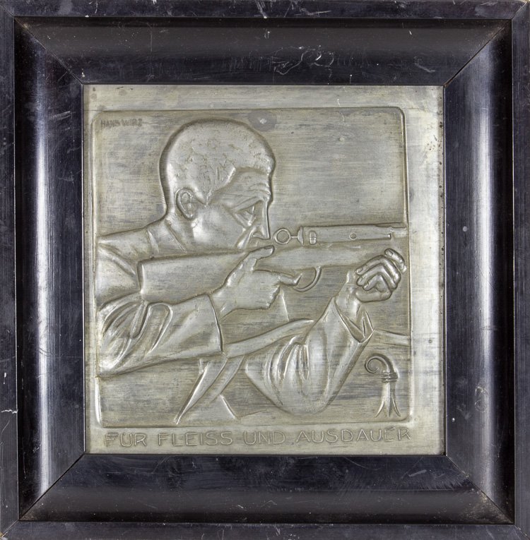 GERMAN SHOOTING AWARD: GERMAN SHOOTING AWARD German shooting award, 7 1/2" x 7 3/4" overall, a framed hammered metal profile of a man aiming a rifle, captioned in German: "FUR FLEISS UND AUSDAUER" ("For Diligence and Persev