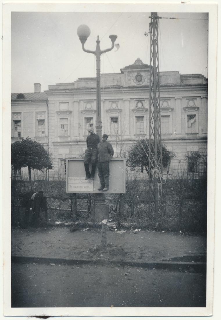 PARTISANS ARE HANGED: PARTISANS ARE HANGED Original photograph, 2 1/2" x 3 1/2" b/w, shows two middle-aged men in cavalry boots, undoubtedly partisands, hanged from a lamp post in a city setting, the sign beneath them indi