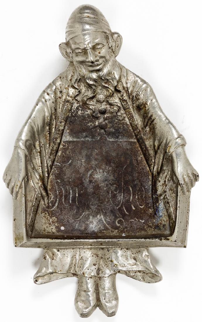 ANTI-SEMITIC ASHTRAY "FOR ASCHE(R)": ANTI-SEMITIC ASHTRAY "FOR ASCHE(R)" Anti-Semitic silver metal ashtray, 7 1/4" tall, 5" wide, a caricature of an Orthodox Jew with hat, long side curls and beard who holds open his coat revealing the e
