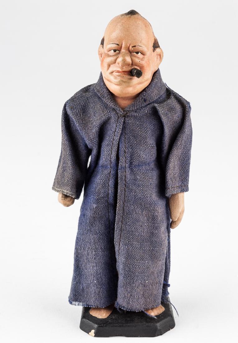 OBSCENE CHURCHILL "POP-UP" STATUE: OBSCENE CHURCHILL "POP-UP" STATUE Crass and derogatory plaster statuette, 7" tall, depicting a cigar-chomping Winston Churchill clad in a loosely fitting blue cloth robe. A yellow string protrudes fro