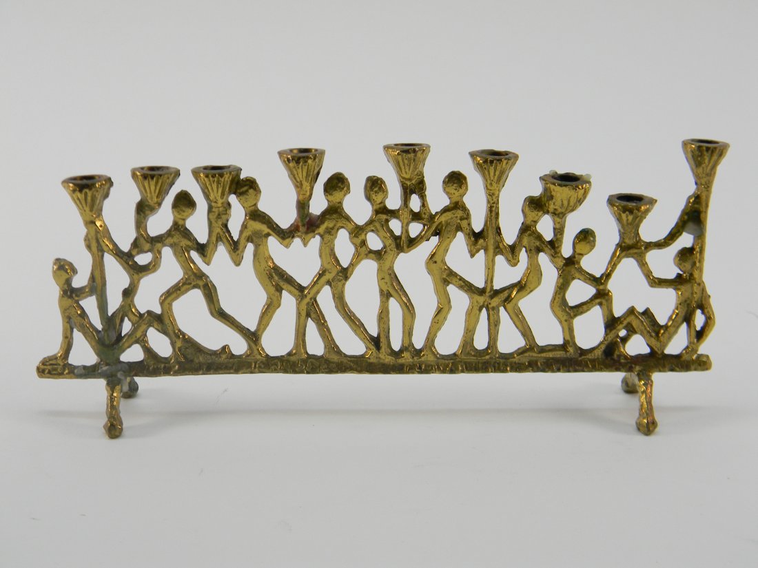Brass Menorah W/ Figures: Menorah with brass people holding up candle holders. Size 9'' long 4'' tall.