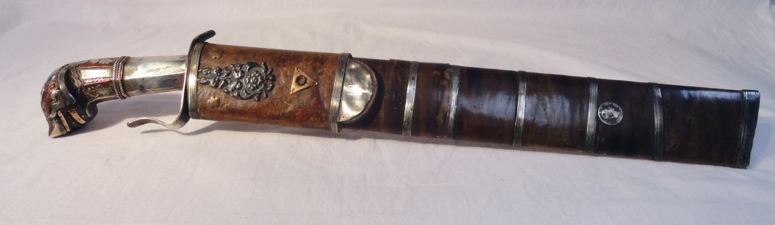 19th Cent Philippine Visayan Bolo Tenegre Sword: Unusual silver adorned 19th century Philippine Visayan Bolo sword with carved deity head hilt. Silver and possibly gold embellishments on the horn sheathed scabbard. There is a 1885 silver coin mounte