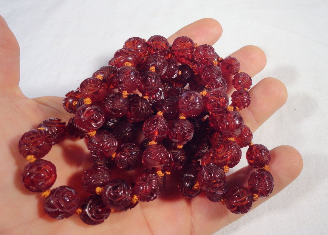 Long Chinese Strand of Cherry Amber Beads Carved 71.9g: Long strand of antique Chinese carved amber beads, there are 101 beads in total, all of a reddish amber color. The beads are carved with decorative and floral designs, and have an even reddish amber c
