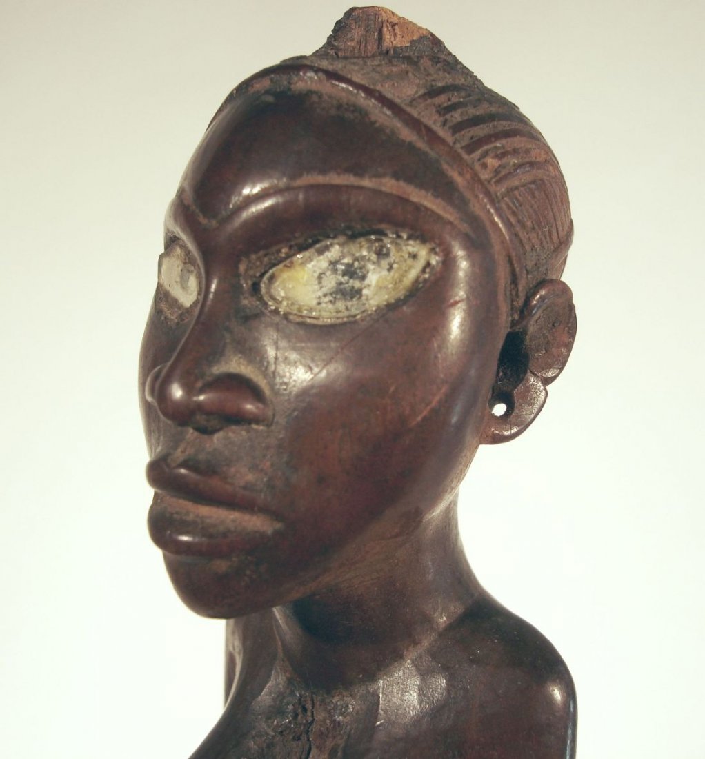 Finely Carved Yombe African Figure Congo Fetish Figure: Well carved African Yombe tribe fetish figure, from the Congo, the female figure with bent arms holding her breasts, and enlarged buttocks, with glass eyes and metal rings around the legs. The patina 